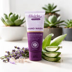 Purple tube of BluWon hand wash with aloe vera slices and lavender on a white surface with plants in the background
