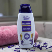 Blue Won shampoo bottle on a bathroom counter with purple flowers and a pink towel.