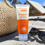 bluwon Sunblock tube on sand with sunglasses and bag in the background